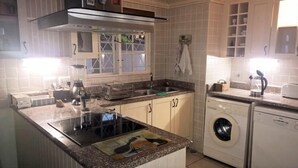 Uma cozinha com fogão embutido, máquina de lavar e micro-ondas.