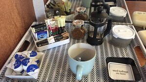 En bakke med instantkaffe, teposer, sukker, mælk og en tepakkekasse.