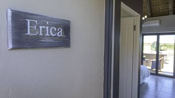 Un cartello con il nome 'Erica' su una parete strutturata, che indica l'ingresso in una stanza con vista su uno spazio esterno.