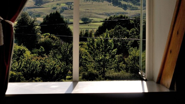 A window with a view of a landscape, including hills and trees. - Knock Out View Clarens (Clarens)