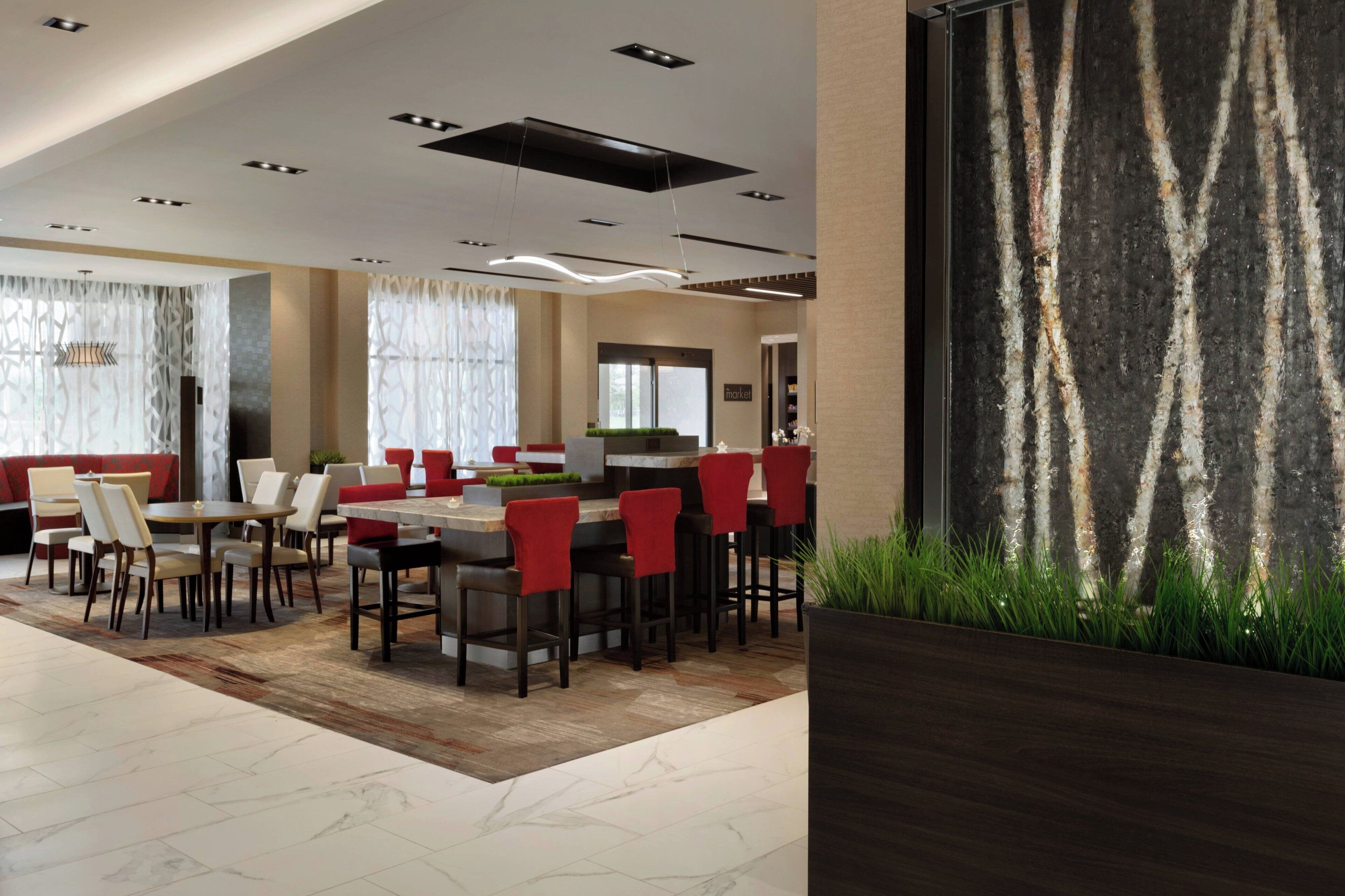 A modern hotel lobby with a bar area, seating arrangements, and a decorative wall.