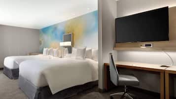 Hotelkamer met twee bedden, een bureau, een stoel, een flatscreen-tv en een muur met een natuurdecoratief muurschildering.
