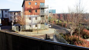 A multi-story building with a balcony, a parking area, and a view of the surrounding area.