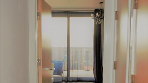 A hallway leading to a balcony with a view of the outside.