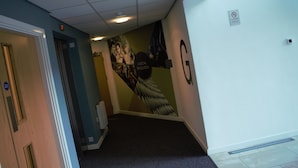 A hallway with a fire exit sign, a no-smoking sign, and a mural on the wall.