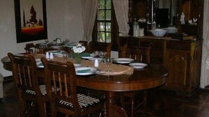 Une salle à manger avec une table ronde en bois, dressée pour quatre personnes, entourée de chaises en bois.