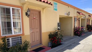 A row of motel buildings with numbered doors, a parking area, and potted plants. - Budget Motel (Mountain View)