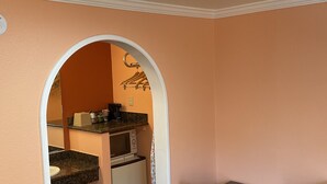 A compact kitchen with a microwave, coffee maker, and a small refrigerator. There is a dining area with a table and chairs. - Budget Motel (Mountain View)