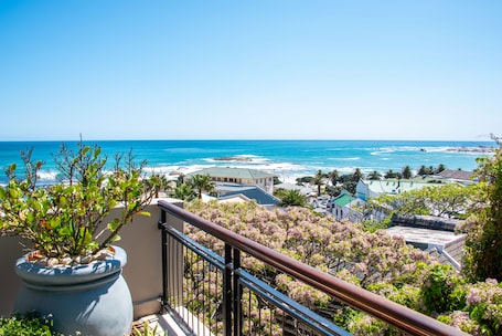 A balcony with a view of the ocean and coastal buildings.
