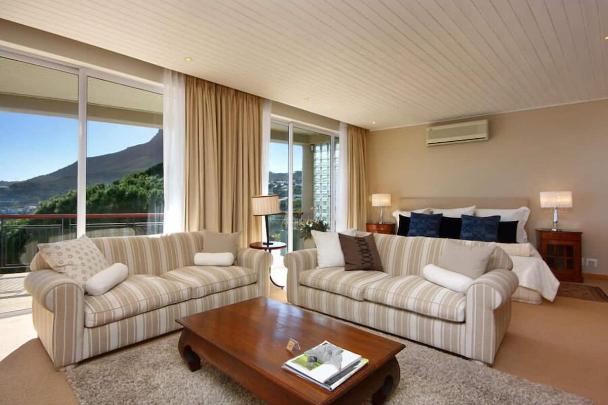 A spacious living room with two striped sofas, a wooden coffee table, and a large window offering a mountain view.