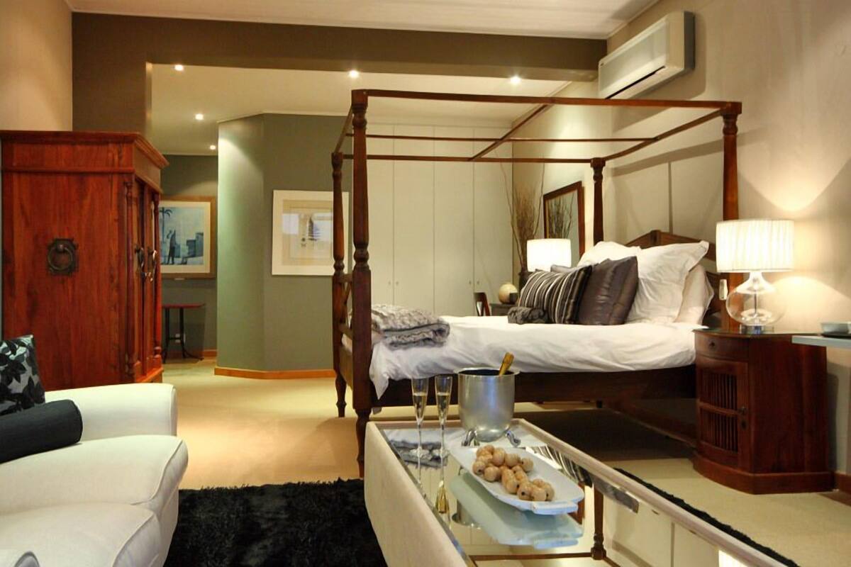 A four-poster bed with a bedside table, a lamp, and a tray with snacks.