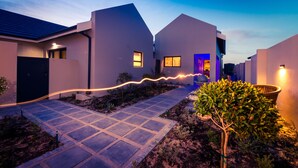 A modern residential building with a paved walkway and a small garden area.