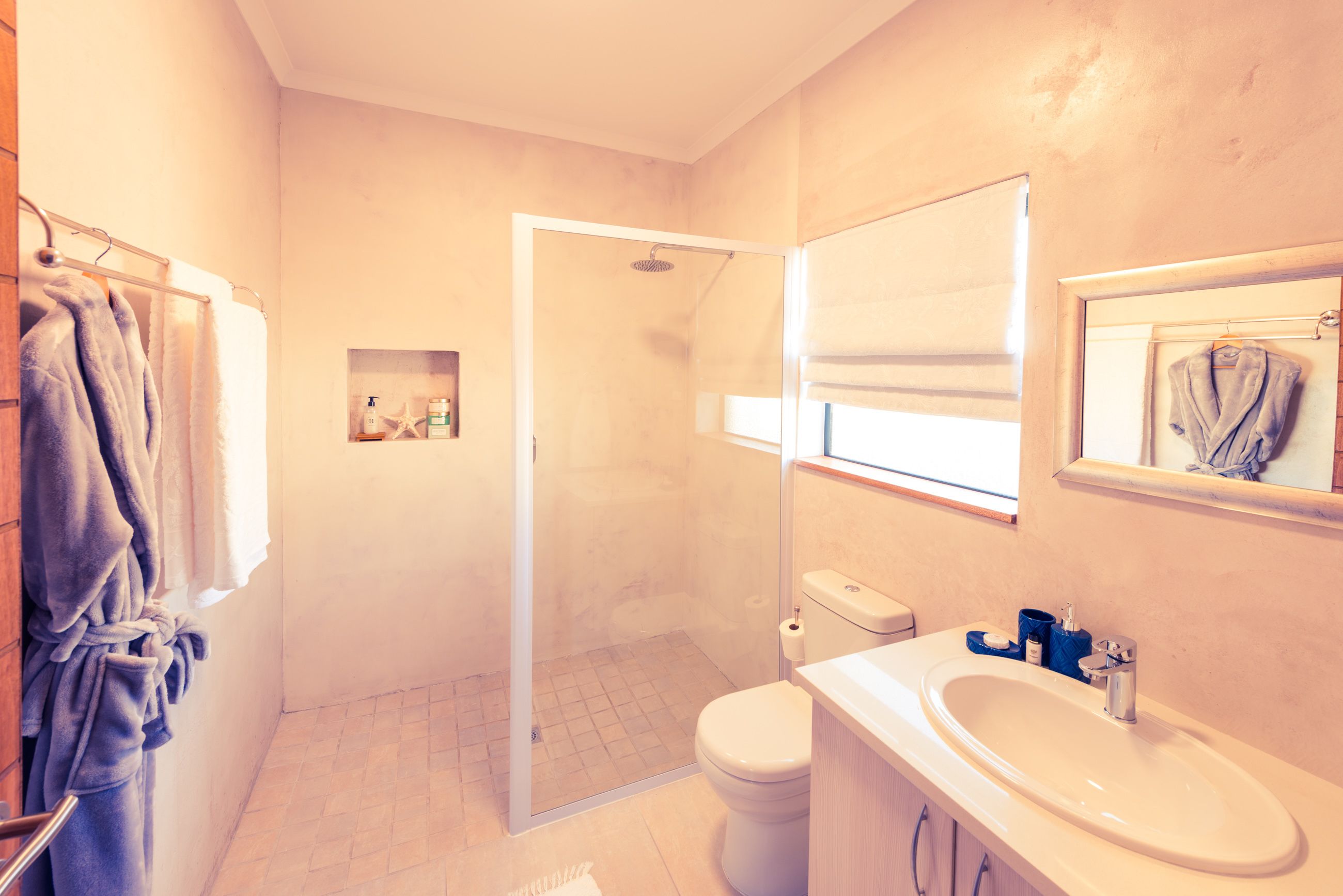 A bathroom with a glass-enclosed shower, a white sink, and a toilet.