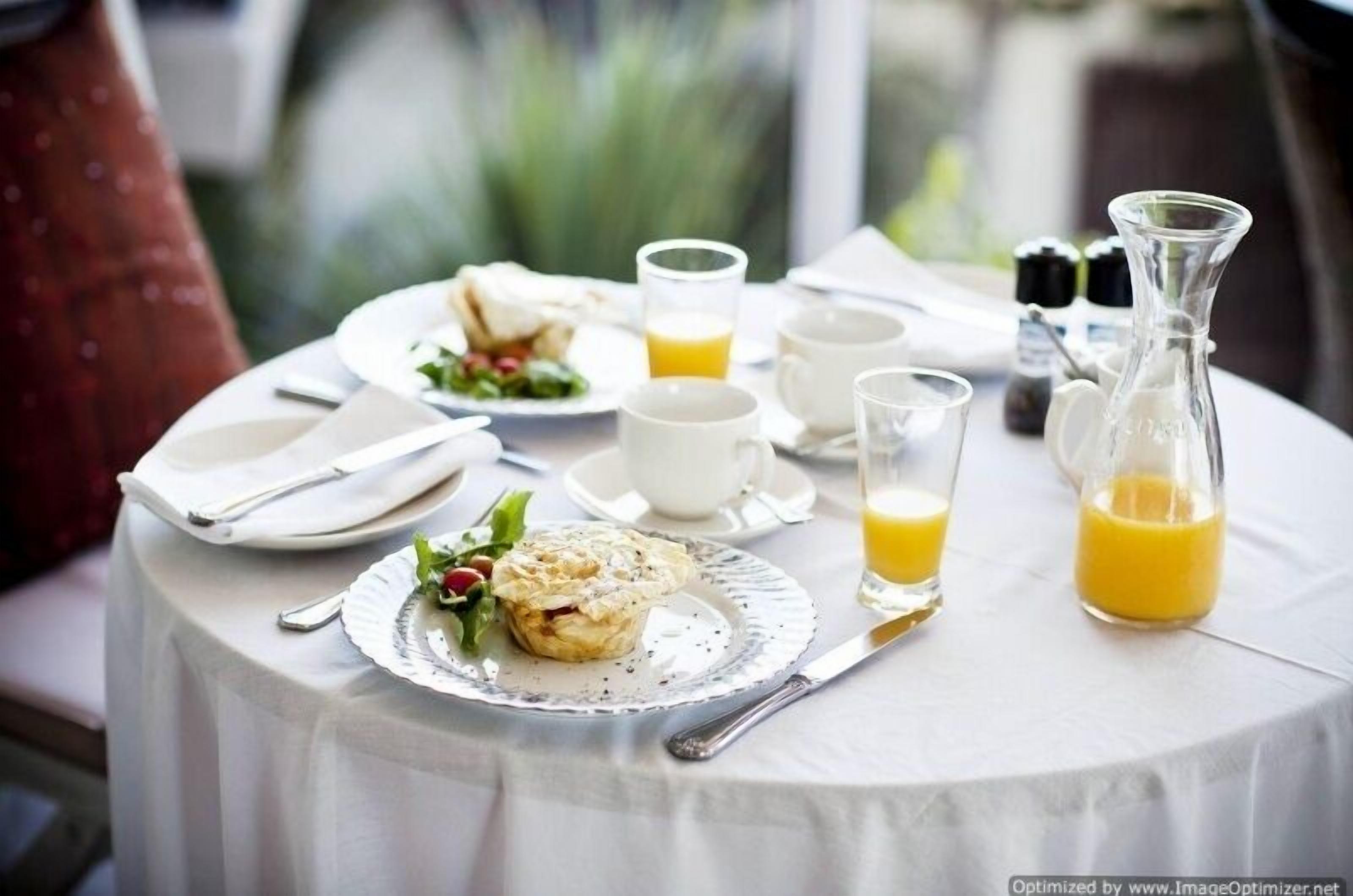 A breakfast setting with plates, cups, and a pitcher of orange juice on a table.