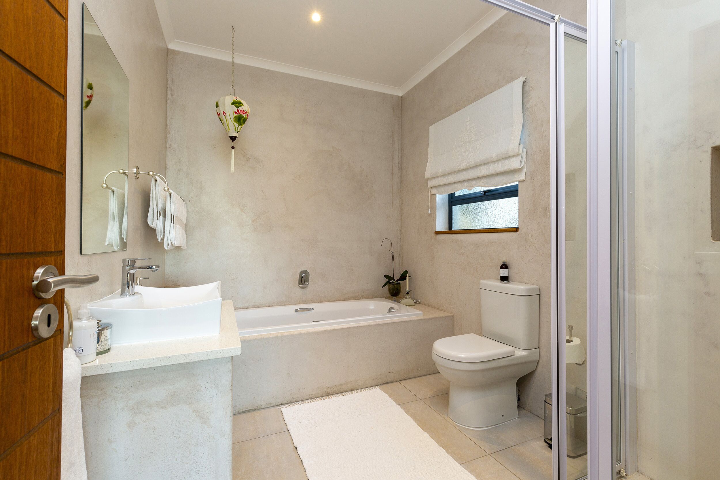 A modern bathroom with a bathtub, sink, toilet, and glass shower enclosure.