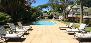 Una piscina al aire libre, sillones reclinables de piscina