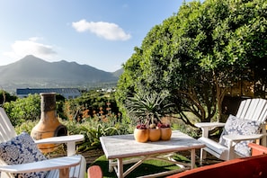 A patio with white chairs, a table, and a large vase.