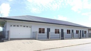 A single-story building with a flat roof, a white garage door, and a paved driveway. - Ximple Appartementen (Paramaribo)