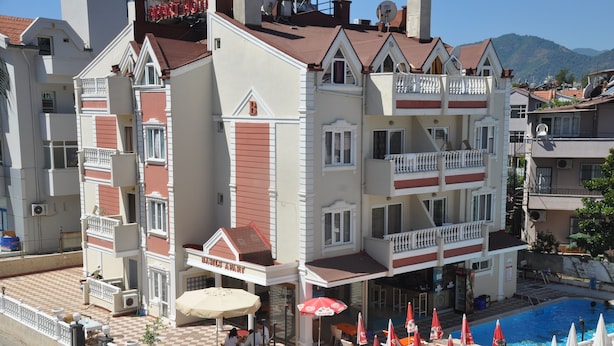 A hotel with a pool area, outdoor seating, and a view of the mountains. - Basil's Apart Hotel (Marmaris)