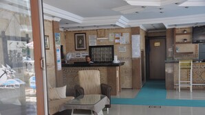 A hotel lobby with a reception desk, a seating area with a sofa and armchairs, and a tiled floor. - Basil's Apart Hotel (Marmaris)