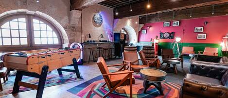 A cozy indoor space with a foosball table, comfortable seating, and a dartboard.