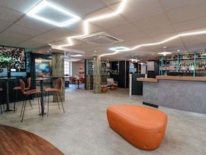 A modern bar area with seating, a neon sign, and a variety of bottles on shelves. - Ibis Budget Marseille Vieux Port (Marseille)