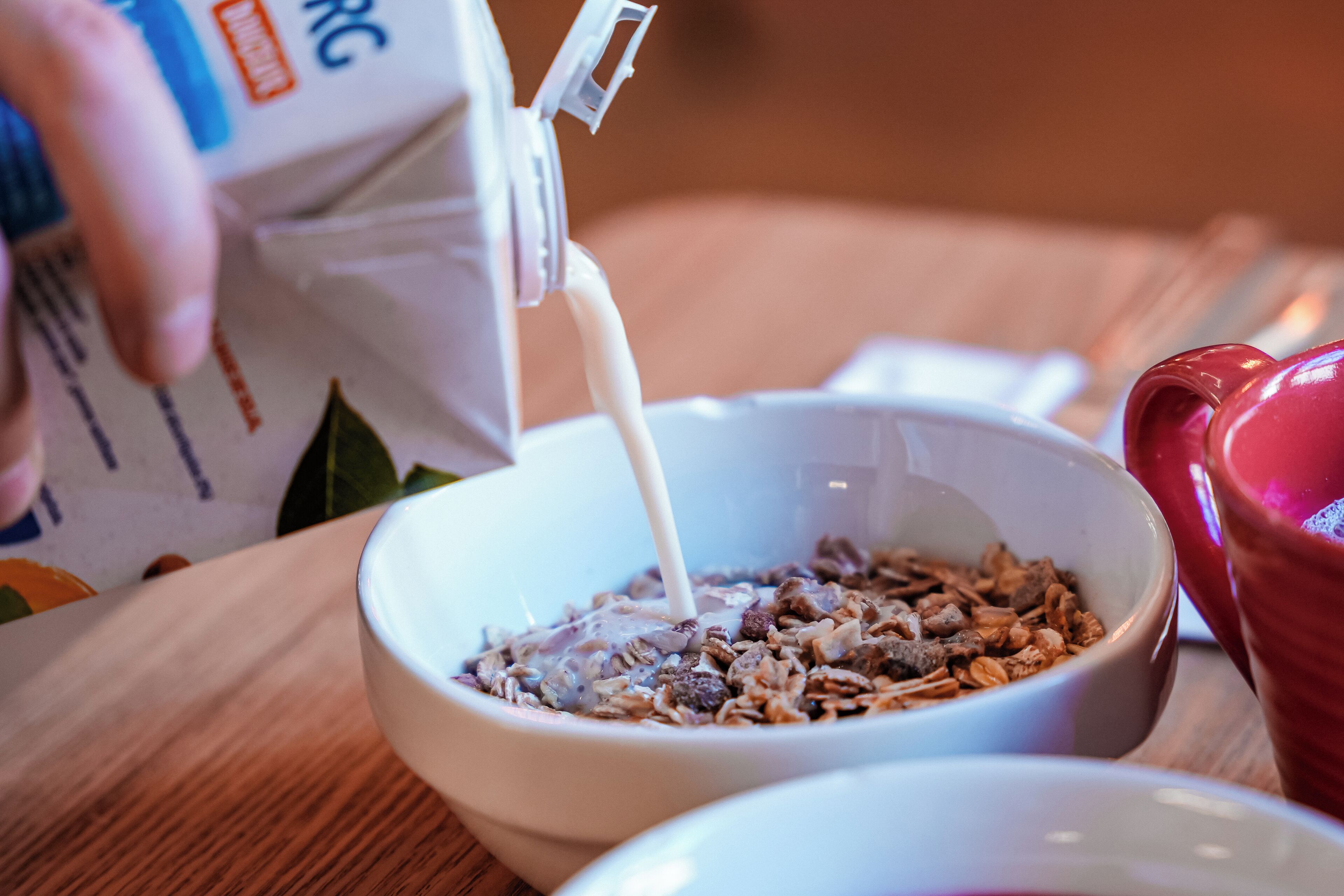 A bowl of cereal with milk being poured into it.