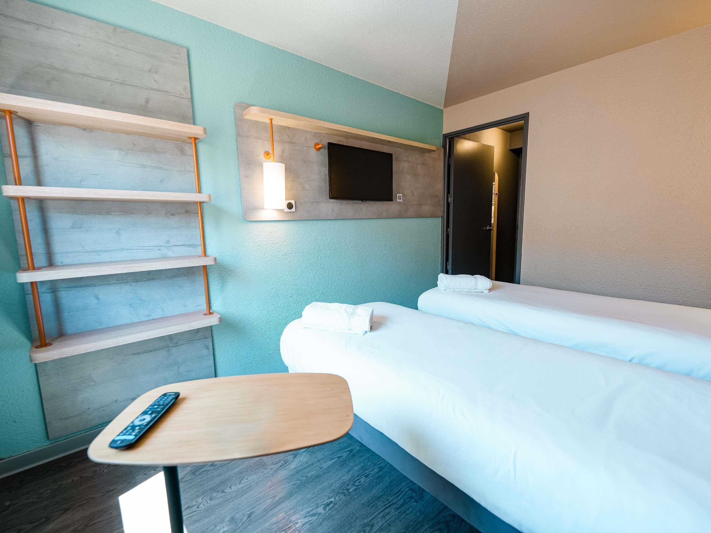 A hotel room with a wooden ladder, a flat-screen TV, a bedside table, and two beds.