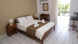 Una habitación de hotel con una cama grande, un escritorio con computadora, televisión y balcón con mobiliario exterior.