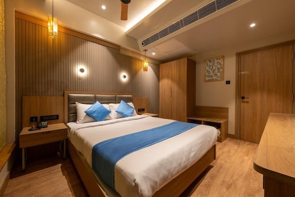 A hotel room with a large bed, wooden headboard, bedside tables, and a wardrobe.