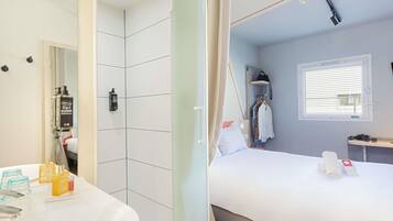 Une chambre d’hôtel avec une salle de bain, un lit, une fenêtre et un miroir.