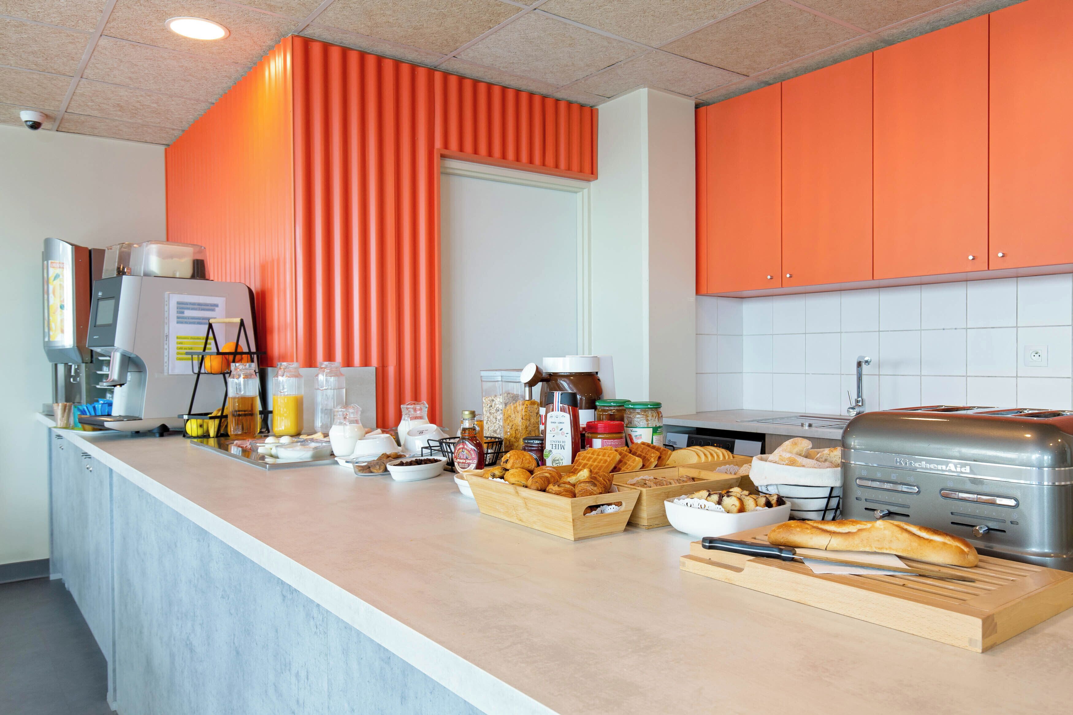 Una cocina con una encimera llena de alimentos para el desayuno, un tostador y una cafetera.