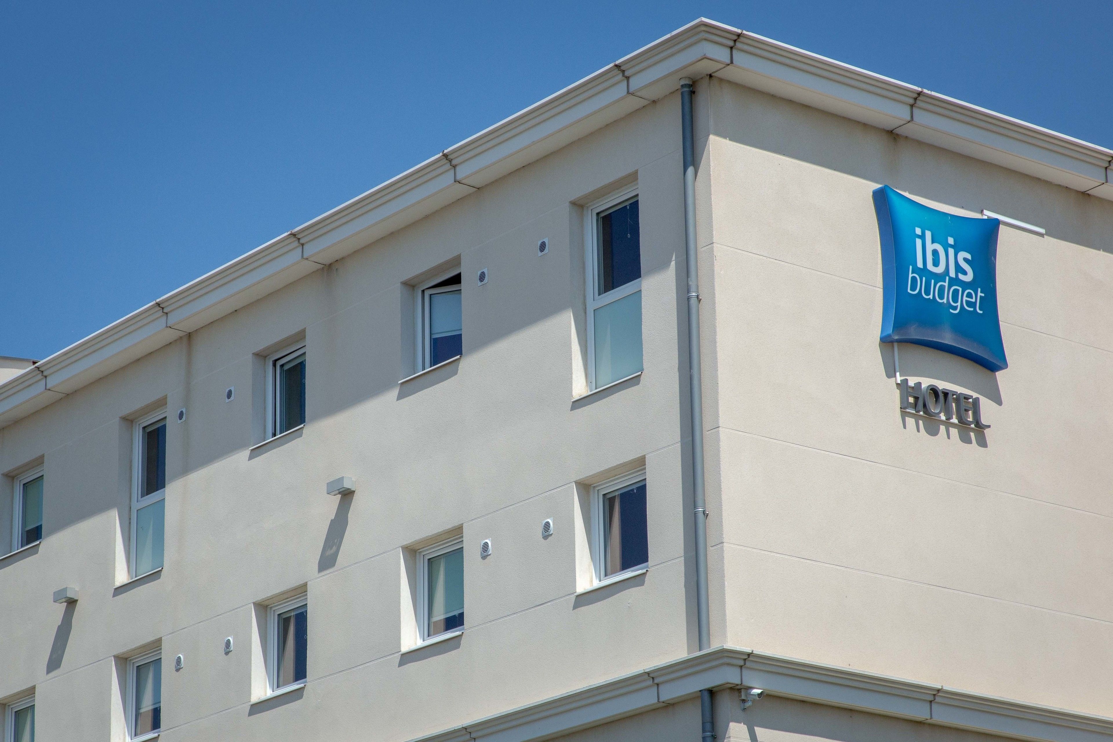 A building with multiple windows and a sign that reads "ibis budget hotel".