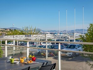A dining area with a view of a parking lot and distant cityscape. - Ibis Budget Marseille L'estaque (Marseille)