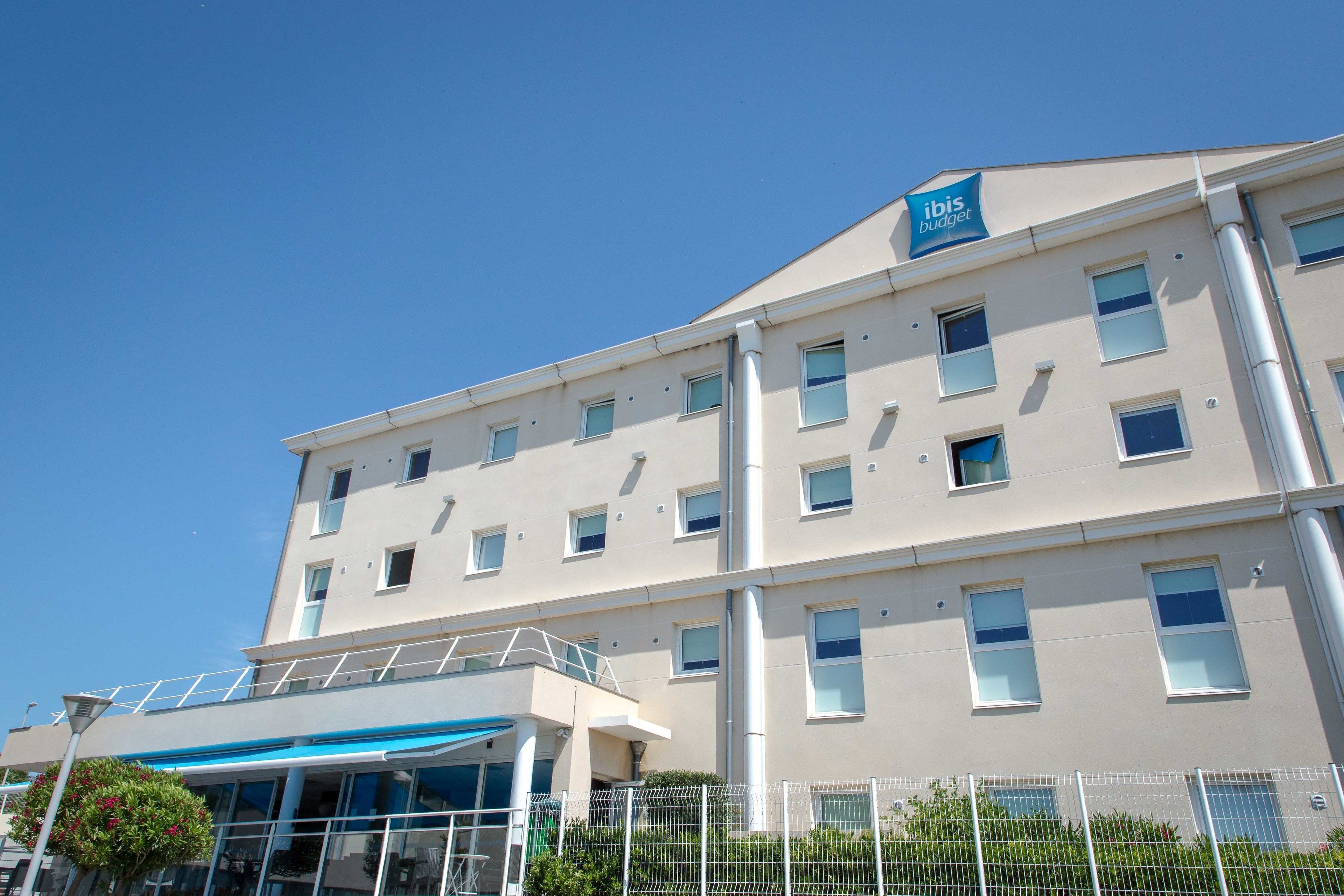 Ein mehrstöckiges Hotel mit schlichter Fassade, zahlreichen Fenstern und einem Schild, das es als ibis budget Hotel kennzeichnet.