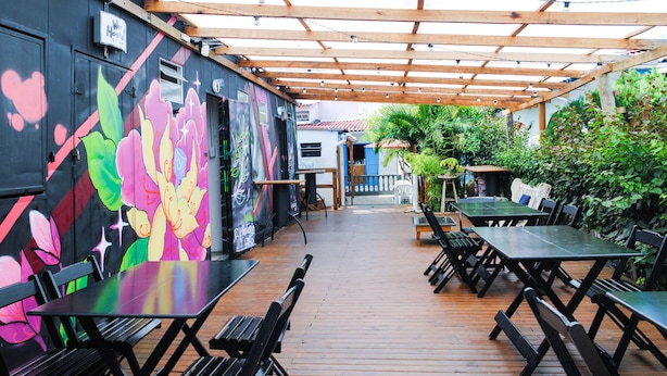 An outdoor patio with wooden tables and benches, surrounded by a wooden pergola. - World Hostel (Florianópolis)