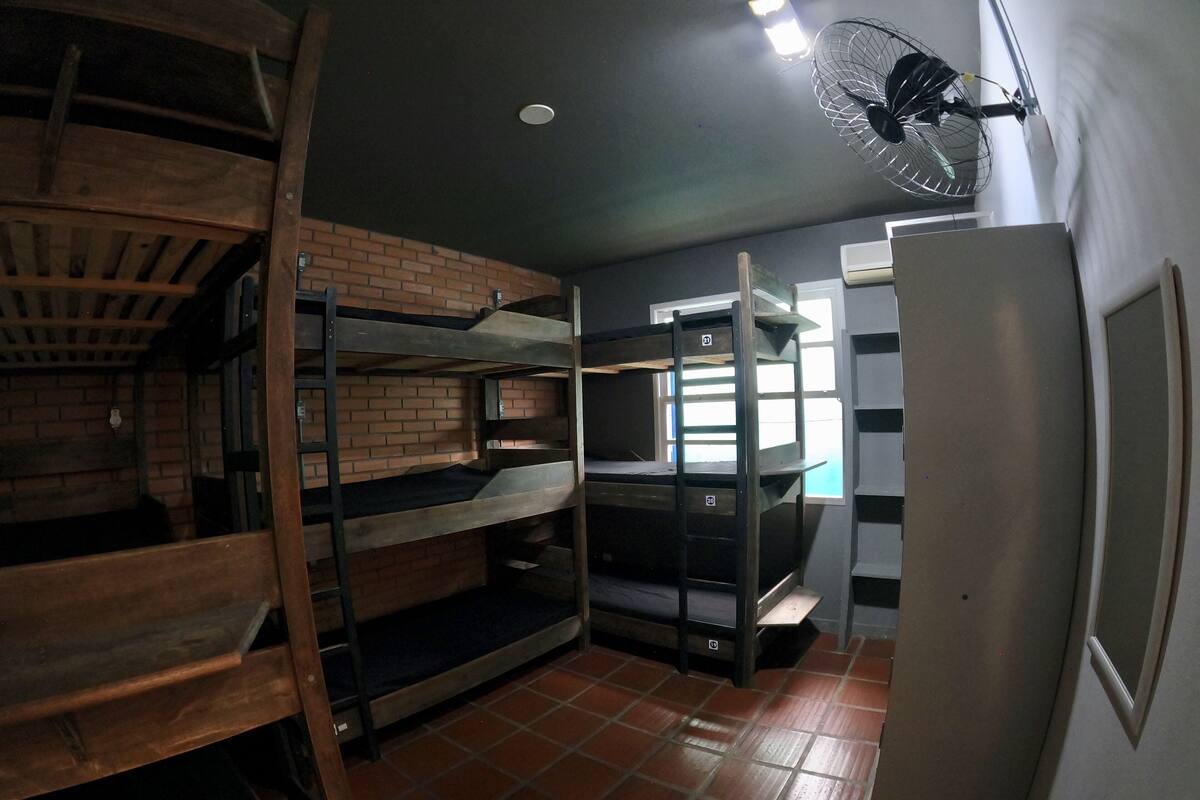 Una stanza del dormitorio con letti a castello, una ventola, una finestra e un pavimento piastrellato.