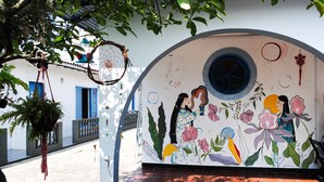 A mural with floral and human figures on a curved wall. - World Hostel (Florianópolis)