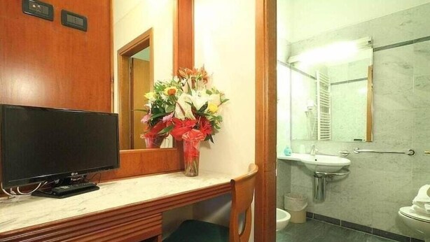 A bathroom with a sink, mirror, and toilet. - Arcadia (Florence)