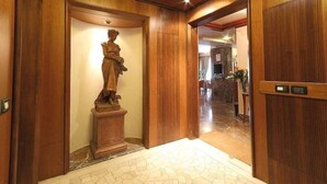A hallway with a wooden statue, a wooden door, and a tiled floor. - Arcadia (Florence)