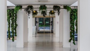 A hotel entrance with a glass door, green foliage decorations, and a clear view of the interior. - Hotel Medena Block A (Seget)