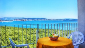 A balcony with a table set for two, overlooking a coastal landscape with a clear view of the sea and distant mountains. - Hotel Medena Block A (Seget)