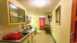 A narrow kitchen with a microwave, a red plastic container, and a sink.
