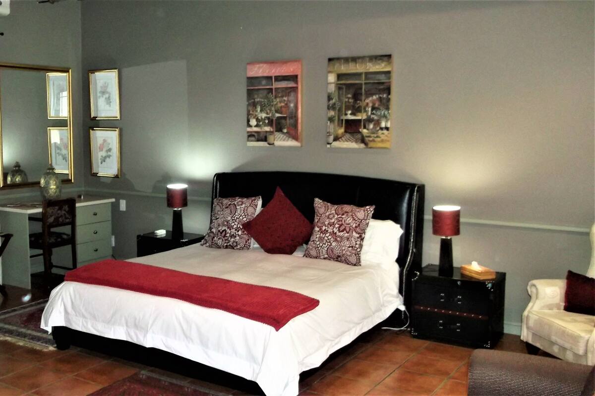 A neatly arranged bedroom with a large bed, a desk, and a chair.