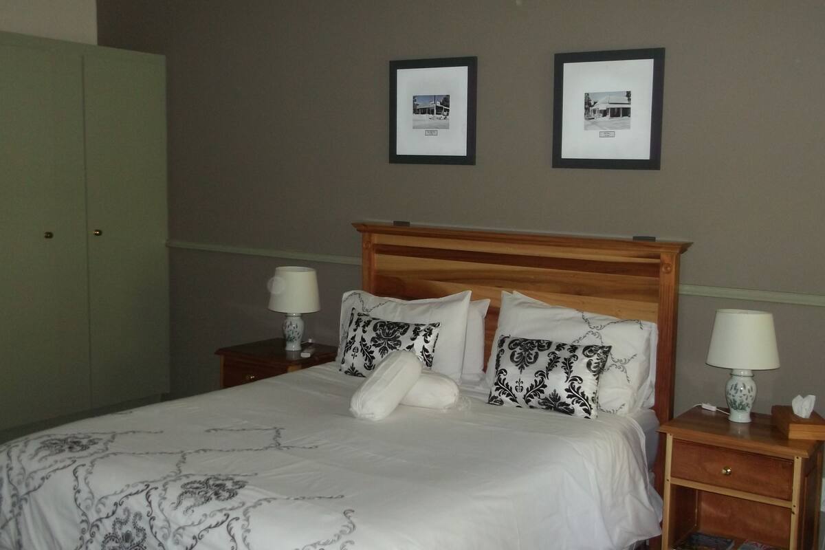 A neatly made bed with patterned bedding, two bedside lamps, and a wooden headboard.
