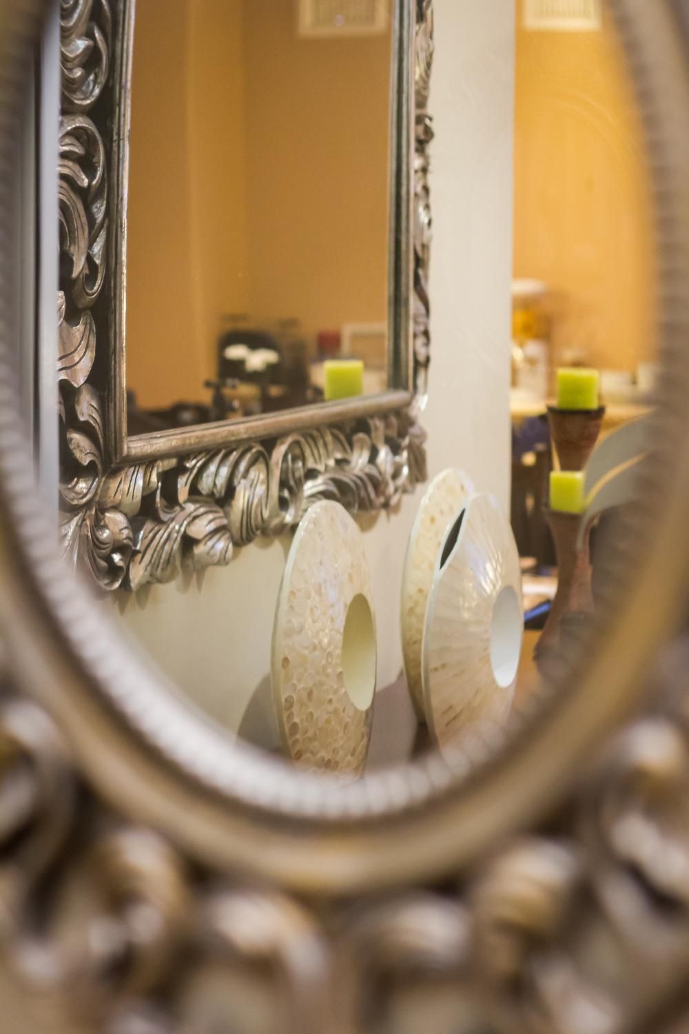 Un baño con un espejo decorativo y un inodoro con un cuenco redondo y con textura.
