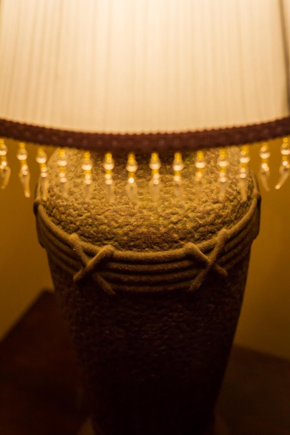 Une lampe avec un pied texturé et un abat-jour blanc.