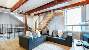 Un salon moderne avec un escalier en bois, un canapé d’angle et un plancher en bois.