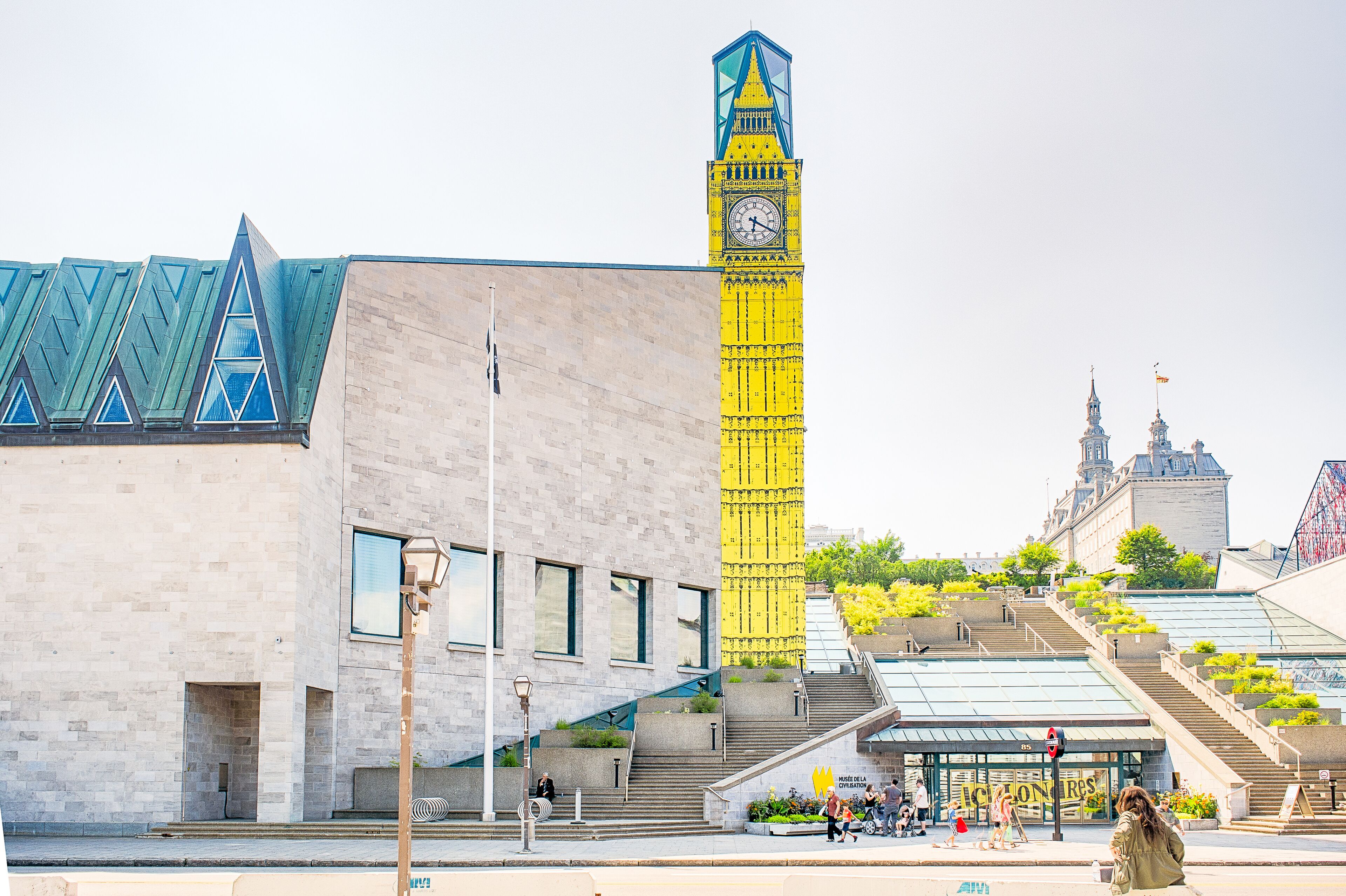 A building with a prominent clock tower and a modern structure with a unique triangular roof.