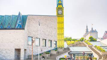 A building with a prominent clock tower and a modern structure with a unique triangular roof.